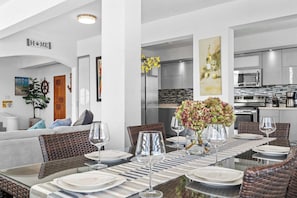 Enjoy meals in this stylish dining area with a long table, wicker chairs, and a sofa.