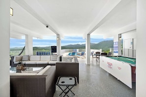 Relax in a spacious area with a high ceiling, large windows offering panoramic views of the surrounding mountains and greenery.