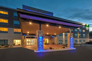 En modern hotellentrén med en överbyggd gångväg, stenkantade pelare och en skylt för Holiday Inn Express & Suites.