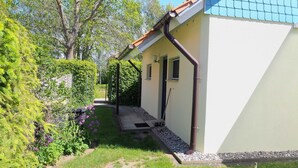 A house with a sloped roof, a small porch, and a garden with various plants and flowers. - Eggers, Sabine Ferienhaus (Insel Poel)
