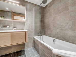 Enjoy a relaxing soak in the sleek bathtub and glass-enclosed shower area.