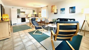 Una sala de estar moderna con un sofá, sillas, una mesa de centro y una zona de comedor con una mesa y sillas.