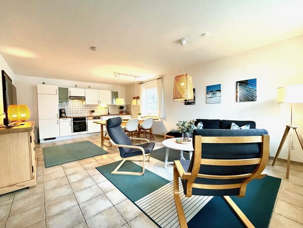 A modern living room with a sofa, chairs, a coffee table, and a dining area with a table and chairs.