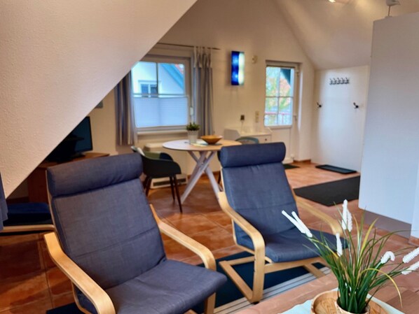 Un salon moderne avec deux fauteuils bleus, une petite table ronde et une plante en pot.