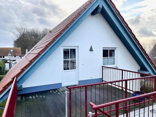 A white building with a red roof and a red railing.