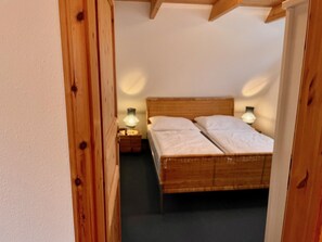 A bedroom with a wooden bed, two bedside lamps, and a wooden door frame.