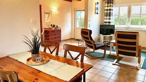 Una sala de estar acogedora con una mesa de comedor de madera, dos sillas, un televisor y una chimenea.