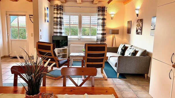 Una sala de estar acogedora con televisor, sofá, sillones y una mesa de comedor.