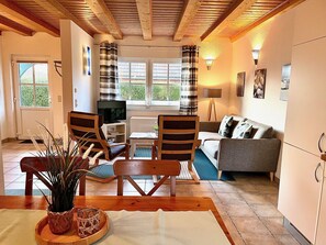 A cozy living room with a TV, sofa, chairs, and a dining table. - Ferienwohnung Haus 4 Wohnung 1 - Ferienhäuser Liethmann (Insel Poel)