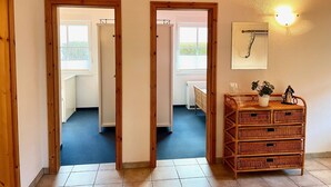 Una habitación con un aparador de madera, una lámpara de pared y un cuadro enmarco.