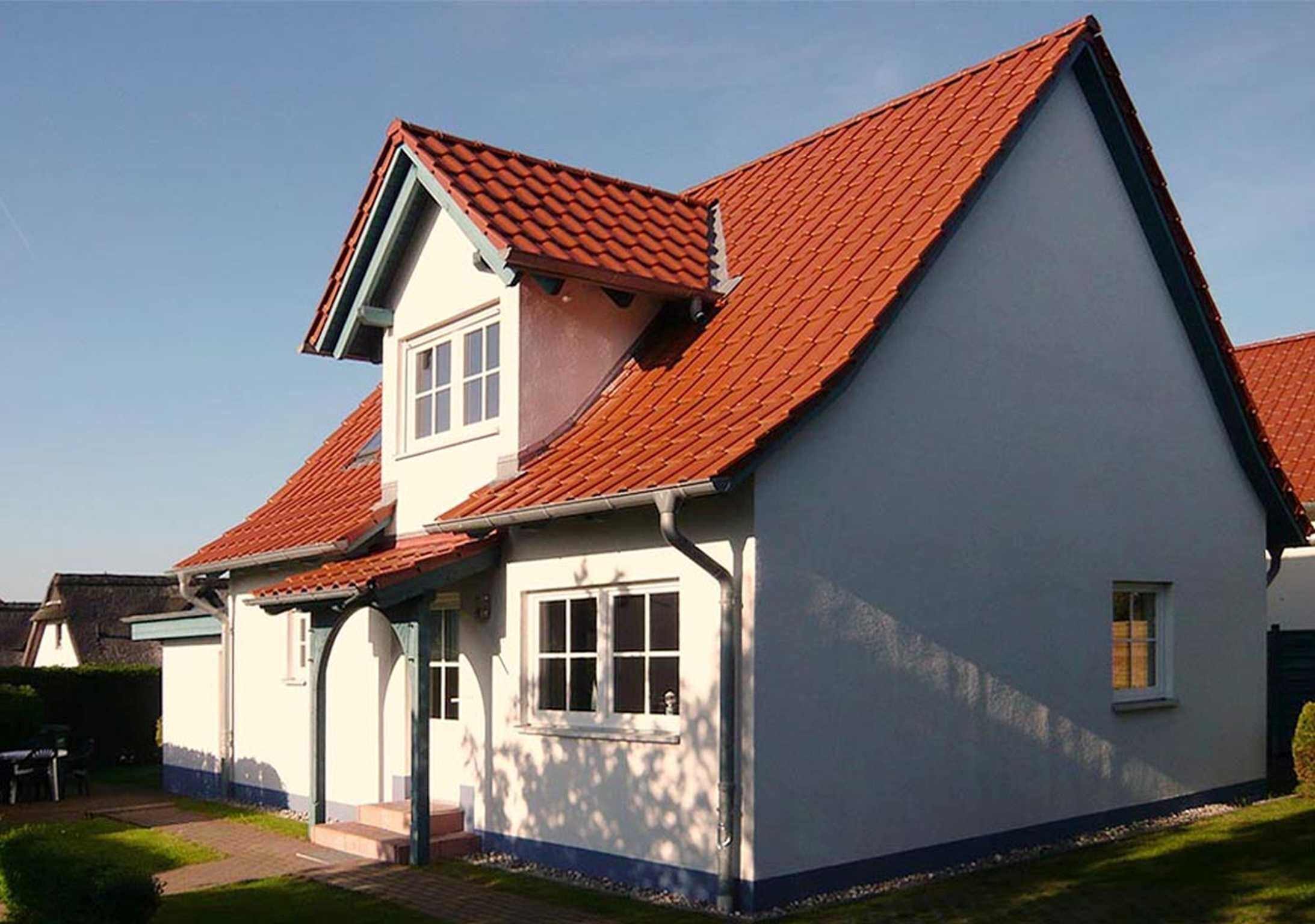 A two-story house with a red-tiled roof and white exterior walls.