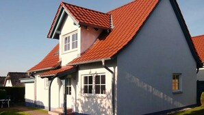 A two-story house with a red-tiled roof and white exterior walls. - Ferienwohnung Haus 3 Wohnung 2 - Ferienhäuser Liethmann (Insel Poel)