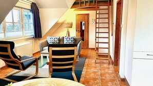 A cozy room with a loft bed, a dining area with a table and chairs, and a kitchen area. - Ferienwohnung Haus 3 Wohnung 2 - Ferienhäuser Liethmann (Insel Poel)