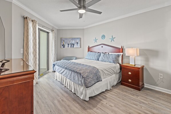 A bedroom with a bed, nightstand, and a ceiling fan.