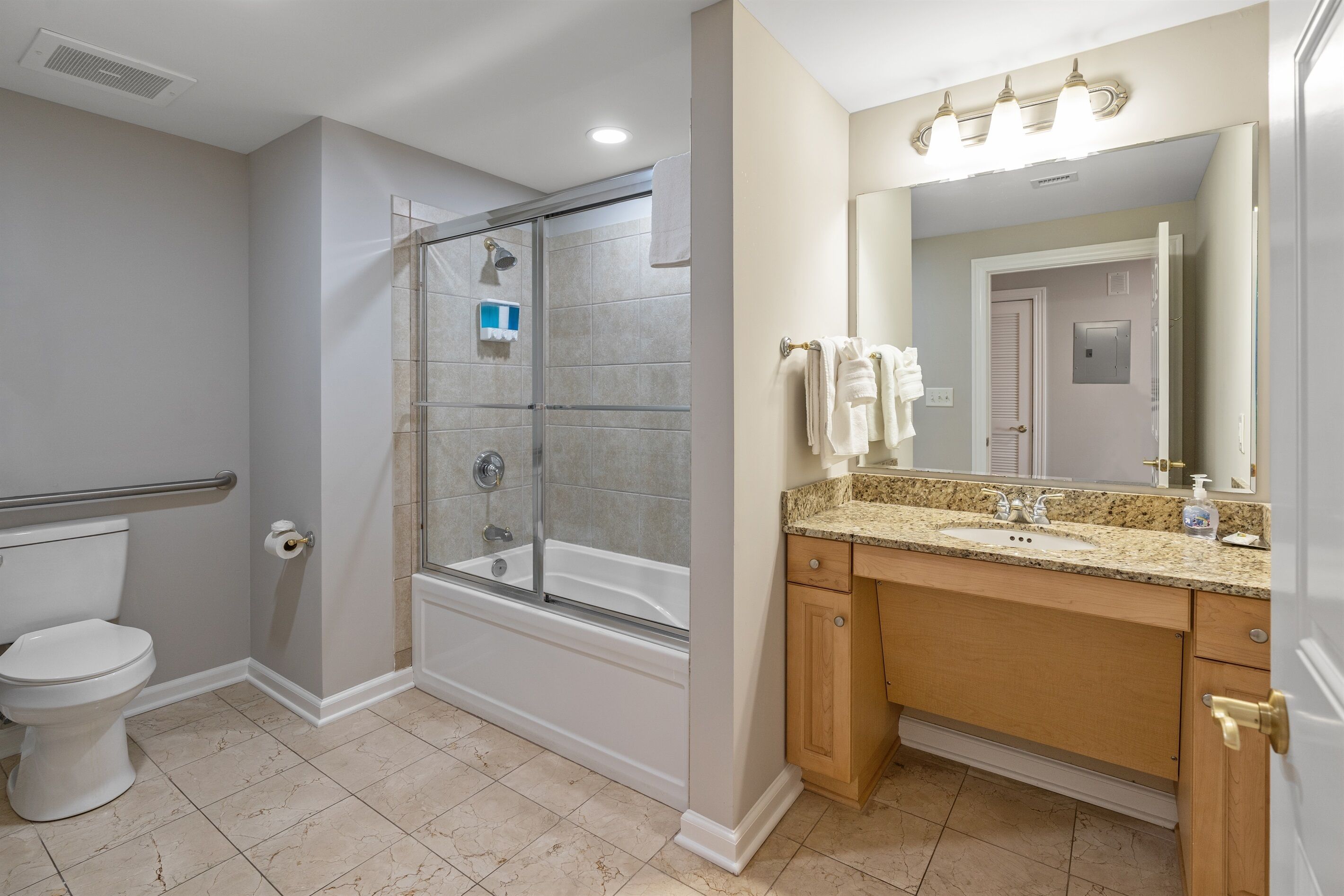 A bathroom with a shower, toilet, sink, and vanity.