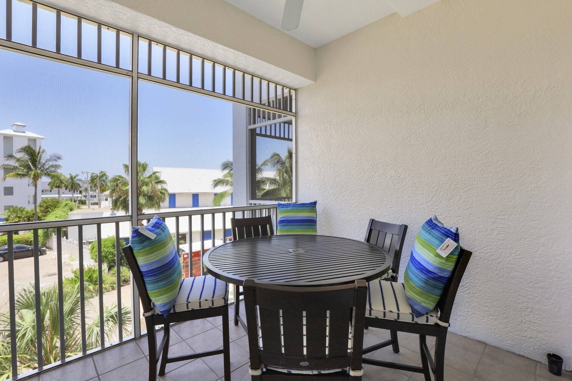 A balcony with a round table and chairs, featuring striped cushions.