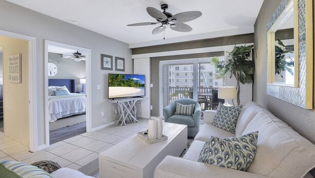 Een moderne woonkamer met een flatscreen televisie, een plafondventilator en een balkon met uitzicht op de stad.
