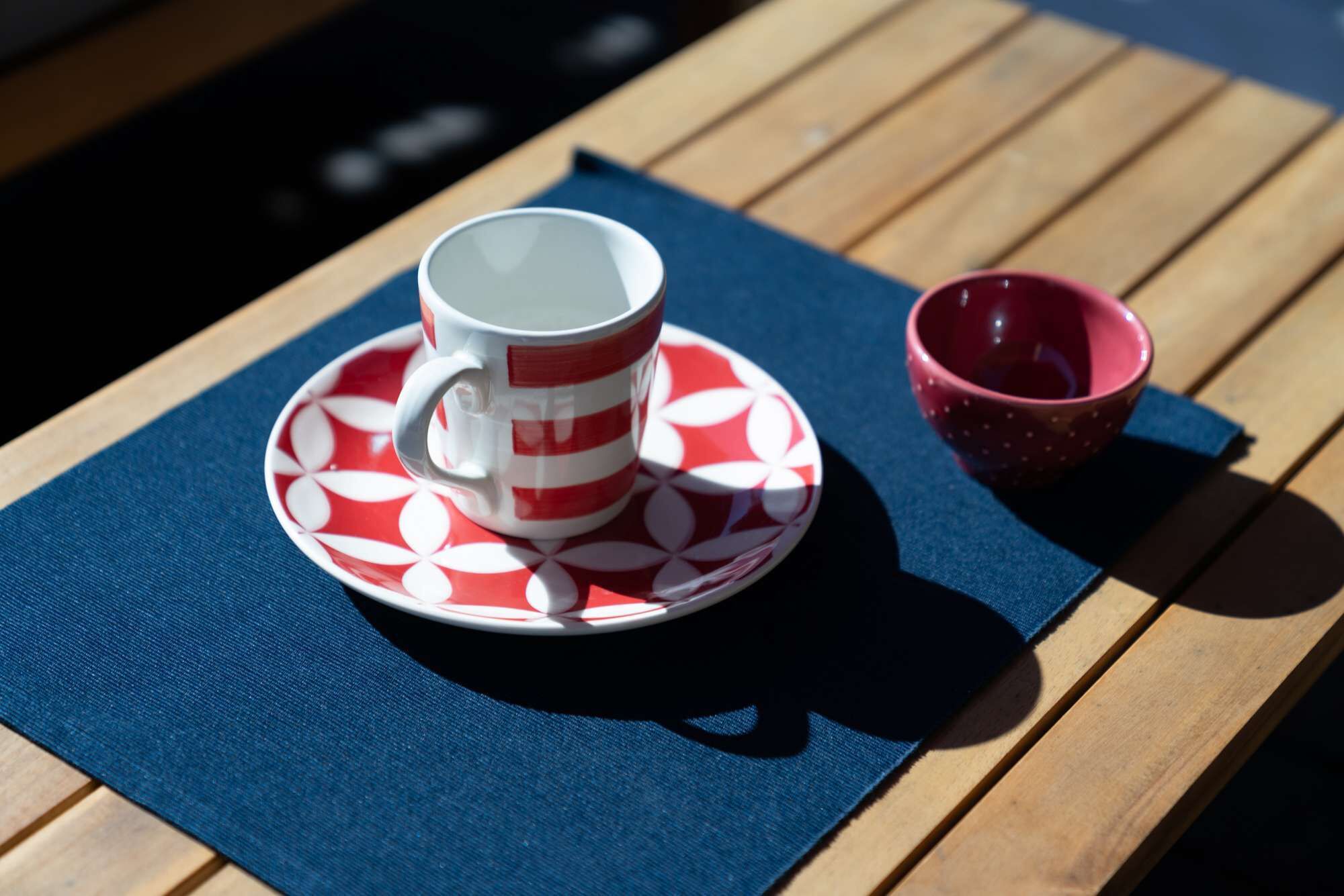 Un tavolo con una tazza e un piattino su un telo blu.