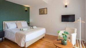 A bedroom with a bed, bedside tables, a TV, a chair, and a plant. - TORRINHA H - Charming studio located in the artistic district of Miguel Bombarda (Porto)