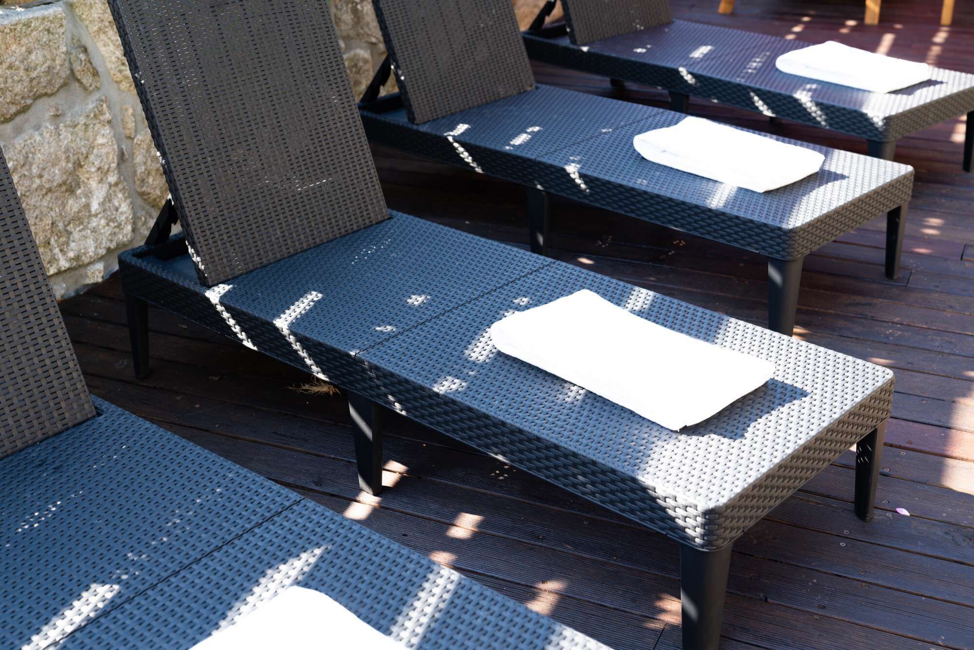 Des fauteuils de jardin confortables, dotés d’assises et de dossiers en fibres tressées, disposés sur une terrasse en bois.