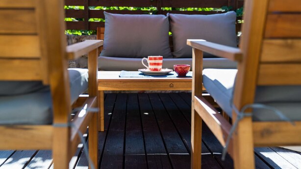 Un terrazza in legno con tavolo e due sedie.