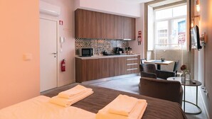 Una habitación de hotel con cama, una kitchenette pequeña, una zona de comedor y vista a la calle.