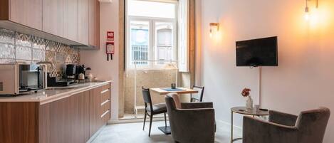 A modern kitchen with wooden cabinets, a dining area with a table and chairs, and a TV mounted on the wall.