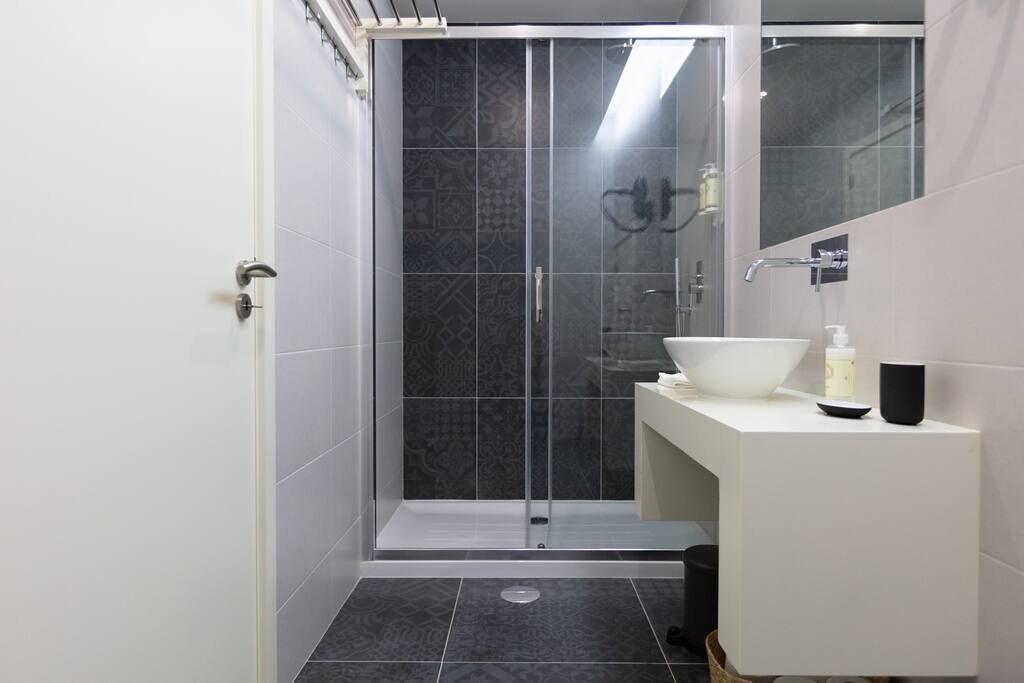 Une salle de bain moderne avec une douche, un lavabo avec un miroir et un meuble-lavabo blanc.