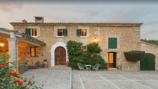 A stone building with a courtyard, outdoor seating, and a green door. - Beautiful Vacation Home "Can Faveta" with Mountain View, Pool, Wi-Fi (Alcudia)