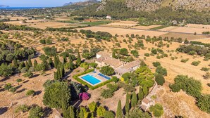 An aerial view of a property with a swimming pool, surrounded by trees and fields, with mountains in the background. - Beautiful Vacation Home "Can Faveta" with Mountain View, Pool, Wi-Fi (Alcudia)