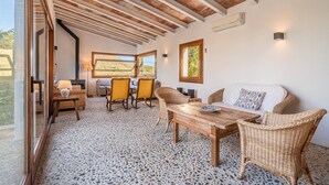 A room with a wooden ceiling, a dining area with chairs and a table, a sofa, and a view through a window. - Beautiful Vacation Home "Can Faveta" with Mountain View, Pool, Wi-Fi (Alcudia)