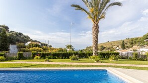 A swimming pool with a clear view of the surrounding landscape, including a palm tree and distant houses. - Holiday Home “Villa Damian” with Mountain View and Garden (Málaga)