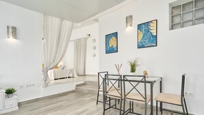 Een moderne kamer met een eettafel, stoelen, een plant en kunstwerken aan de wanden.