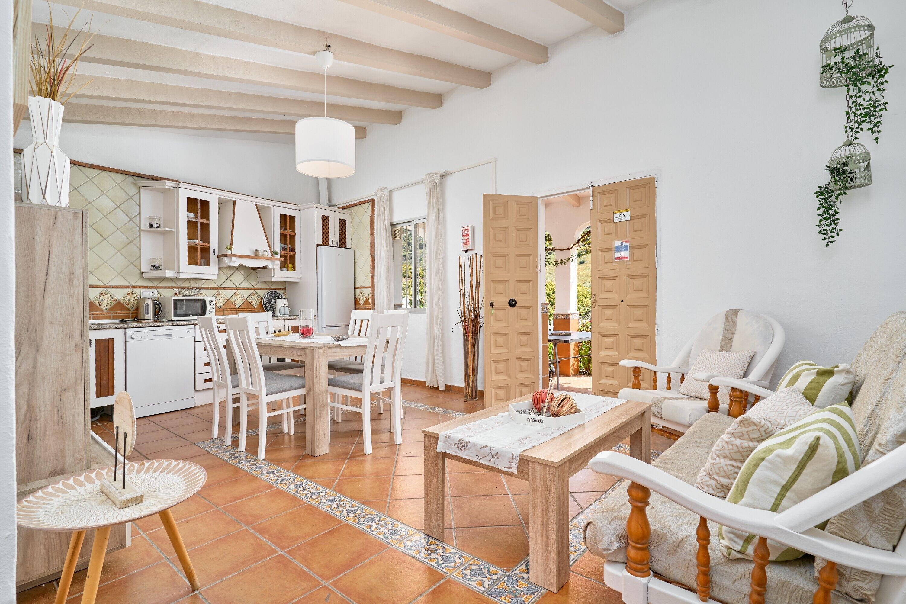 Eine moderne Küche mit weißen Schränken, ein Essbereich mit Tisch und Stühlen sowie eine gemütliche Sitzecke mit Sofa und Sesseln.