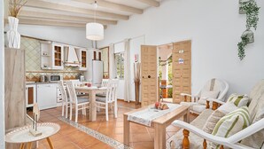 Een moderne keuken met witte kastjes, een eethoek met tafel en stoelen, en een gezellige zithoek met een bank en fauteuils.