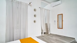 Een hotelkamer met een bed, gordijnen, een spiegel en een houten vloer.