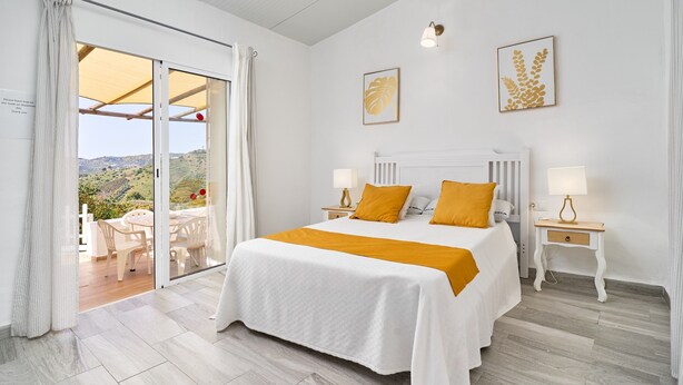 Een slaapkamer met een bed, twee nachtkastjes, een uitzicht door een schuifdeur en een balkon.