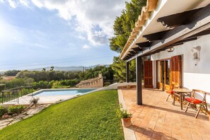 Une piscine, une terrasse avec des chaises et une vue sur la campagne.