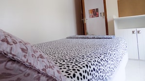 Een slaapkamer met een bed, een deur en een witte kledingkast.