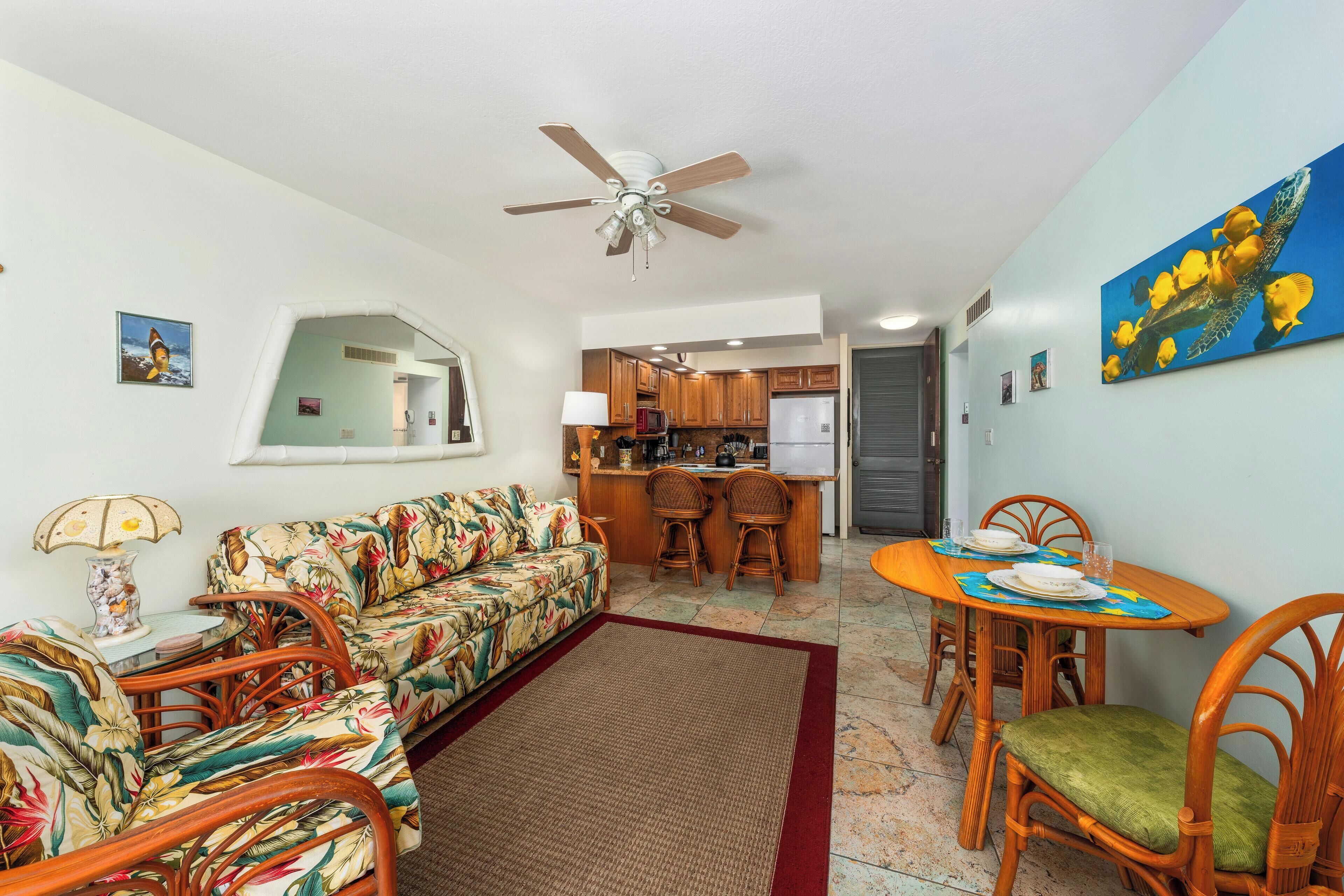A living room with a sofa, chairs, a dining table, and a kitchen in the background.