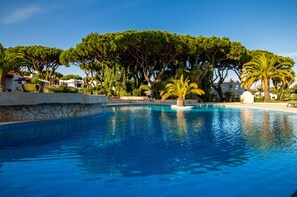 Une piscine bordée de pierres, entourée d’arbres, et sur laquelle on peut lire l’inscription « PORTUGUESA ».