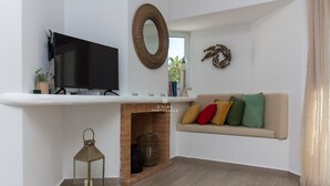 Un salón con una televisión de pantalla plana, chimenea, sofá con cojines y un espejo en la pared.