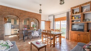 A spacious living area with a dining table, sofas, and a TV. - Holiday Home "Casa Rural Villena" with Sea View, Wi-Fi, Pool & Terrace (Frigiliana)