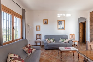 Un salon comprenant un canapé, des fauteuils, une table basse et des œuvres d’art accrochées aux murs.