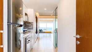 A modern kitchen with stainless steel appliances, a stone backsplash, and a view to a balcony with a glass door. - L'Armatore LOFT"- Italian Style (Puerto Vallarta)