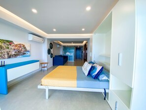 A modern bedroom with a bed, a desk, and a wall-mounted air conditioner. - L'Armatore LOFT"- Italian Style (Puerto Vallarta)