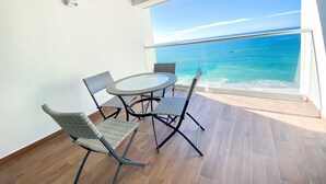 A balcony with a round table and four chairs, overlooking a clear blue sea. - L'Armatore LOFT"- Italian Style (Puerto Vallarta)