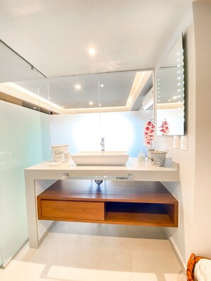 A modern bathroom with a white sink, a mirror above it, and a wooden cabinet below. - L'Armatore LOFT"- Italian Style (Puerto Vallarta)