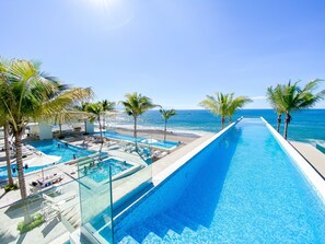 Una piscina al aire libre, una piscina con borde infinito, tumbonas