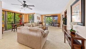 Ein geräumiges Wohnzimmer mit einer großen Couch, einem Deckenventilator und einem Essbereich mit Tisch und Stühlen.